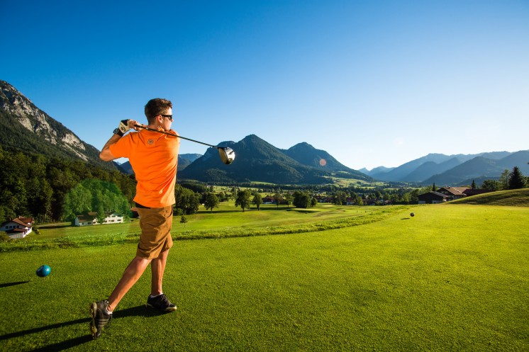 Ein Mann schlägt einen Ball auf einem grünen Platz während seinem Golf-Kurzurlaub in Bayern