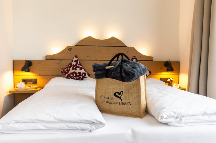 Graue Bademäntel in einer Tasche auf einem frisch gemachten Hotelbett