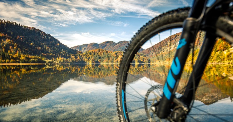 Blick durch einen Fahrradreifen auf einen schönen See und Bergpanorama