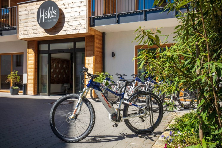 Mehrere blau-weißes Fahrräder, dahinter das Hotel mit dem HELDs Logo