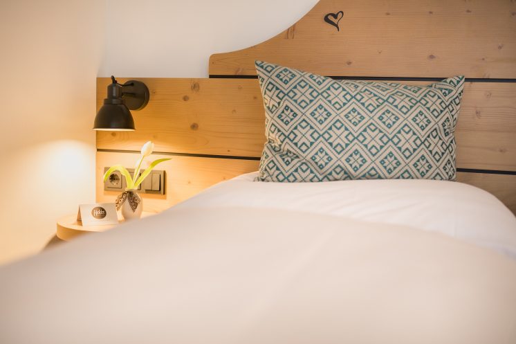 Ein Einzelbett der Juniorsuite des Hotels in Ruhpolding mit einem blauen Kissen