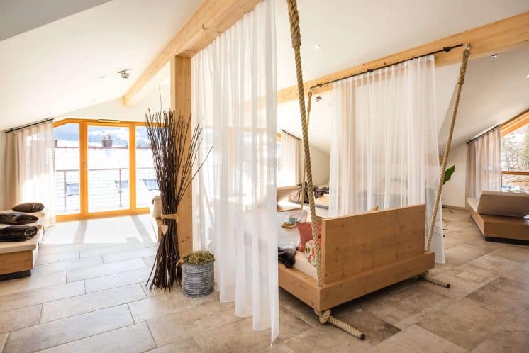 Wellnessliegen mit Decken, Kissen, einer Zeitschrift und Tee mit Snacks auf seitlicher Ablage.