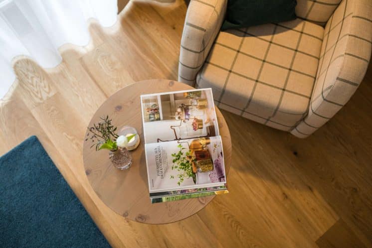 helds-vitalhotel-ruhpolding-zimmer_heldenparadies Aufnahme eines runden Tischs von oben, auf dem Tisch ein Magazin und eine Vase mit Blumen